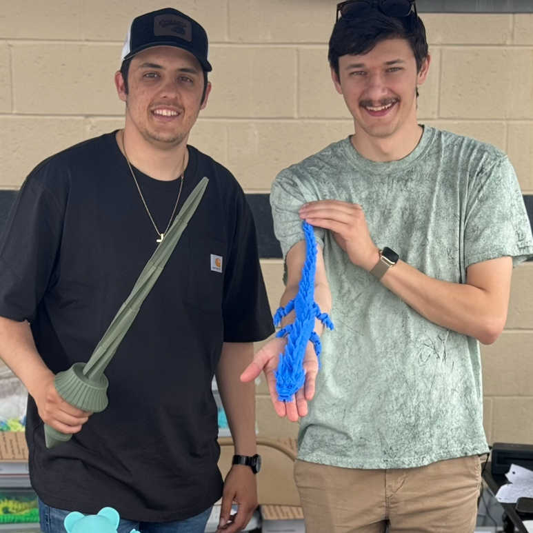 Two men standing behind a table filled with colorful toys, including action figures and plushies.